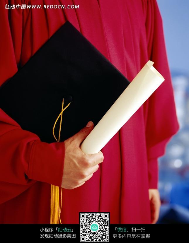 穿着红色学位服夹着学位帽拿白色纸张的人物图