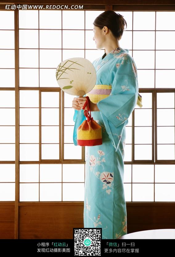 穿蓝色和服系黄带的拿着扇子的女子的侧面图片