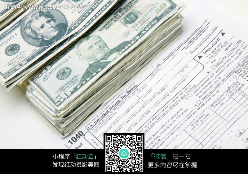 压在个人所得税申报表上的钞票图片-生活用品