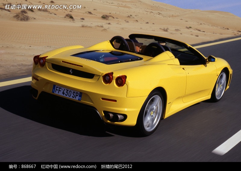 在荒漠公路上行驶的黄色敞篷跑车图片-现代科