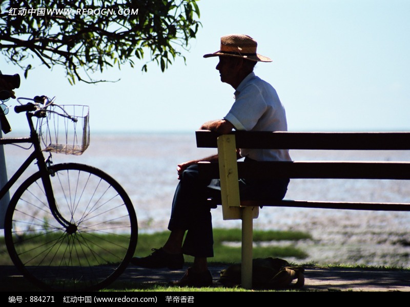 坐在长椅上的戴帽子的男子和自行车图片-风景