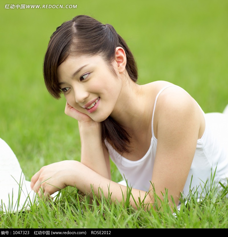 单手托腮趴在草地上微笑的看着帽子的美女设计图片