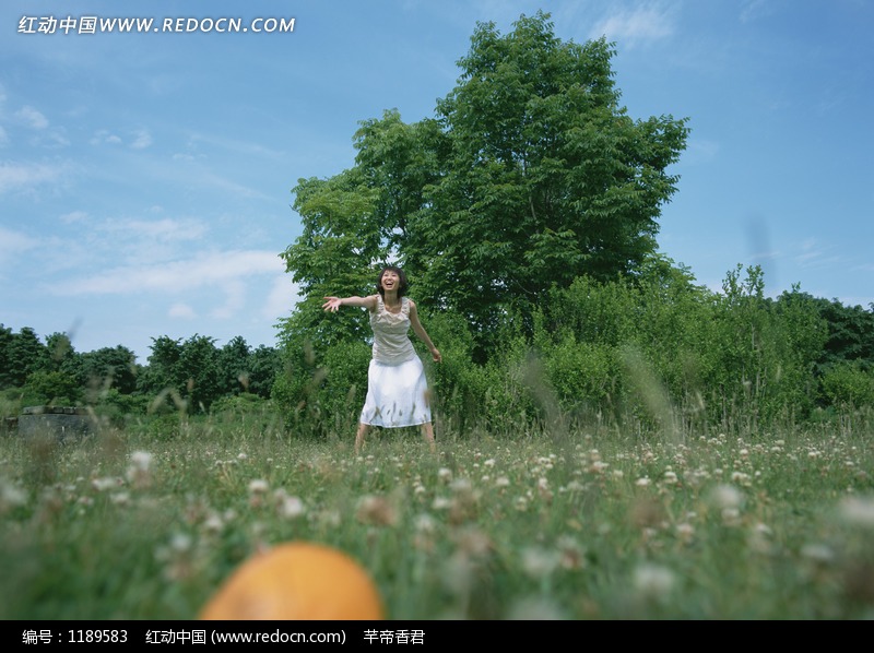 草地上向前伸手弯腰微笑的美女图片-人物图片