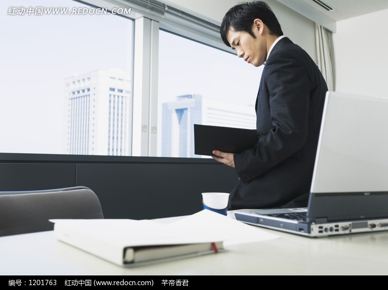 坐在办公桌上看文件的男人图片(编号:1201763